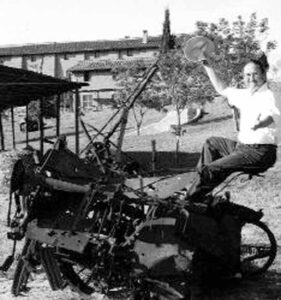 Warner sits on a rusting farm implement at the experiment farm outside of Rome.