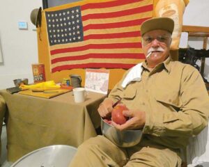 Stanley Rikard, shows onlookers the proper way to peel potatoes if you were on KP (kitchen police) while serving in the Army. He also demonstrates the early days when everyone smoked everywhere and anywhere with a homemade cigarette.