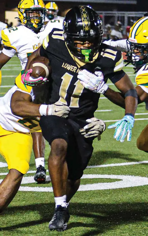 Lower Richland’s Solomon Kelson powers through the tackles of Spring Valley’s Marcel Goodwin and Brent Mills.