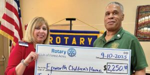 Epworth’s Beth Williams accepts a donation from Rotary’s Stan Holland.